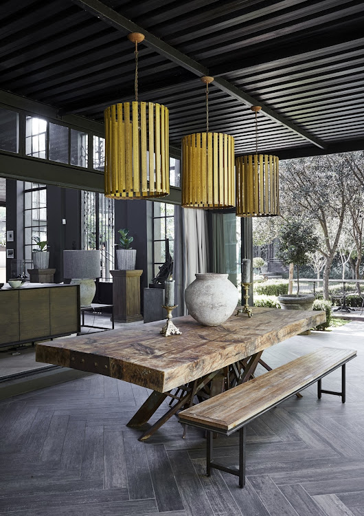 A covered patio between the main living area and vegetable garden makes for a beautiful outdoor dining area. The pendant lights are made from vintage rulers.