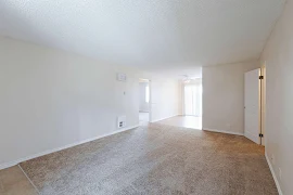 Living room with carpeted flooring, white trim, and neutral wall open to the dining area 