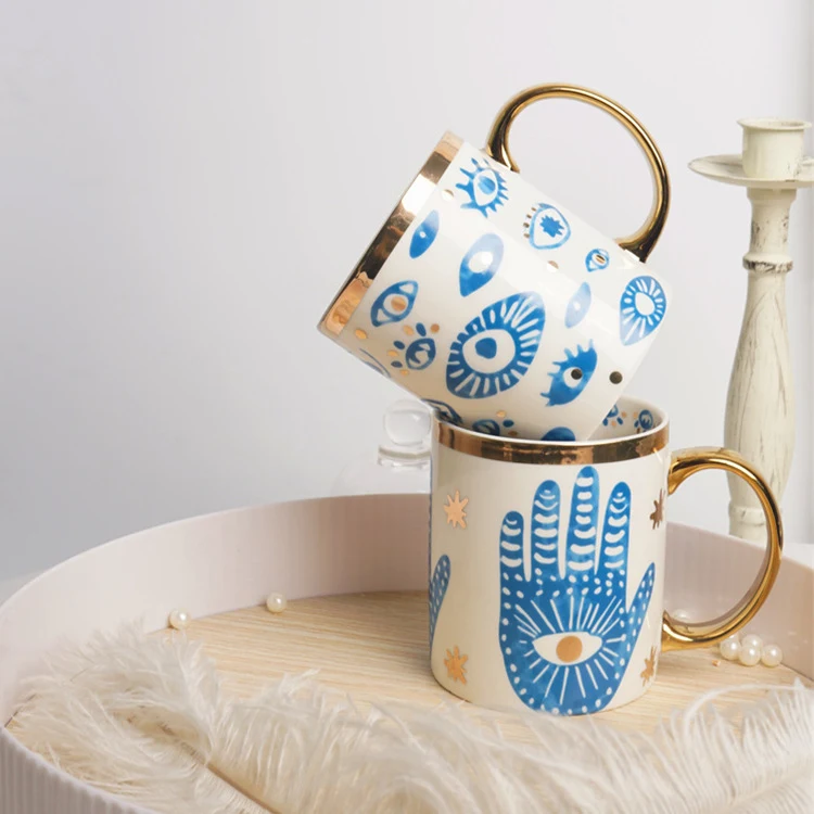 Keramische mokken met hand- en oogafdruk, gouden stickers en decoratief dienblad voor een stijlvol interieur.
