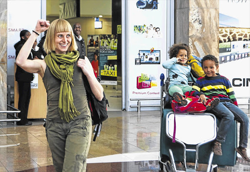 Activist Liv Shange after arriving at OR Tambo International airport yesterday with her children Nomanyano, 5, and Nila, 8. She was welcomed by members of the Workers' and Socialist Party