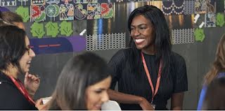 Woman in focus, conversing with people, smiling.