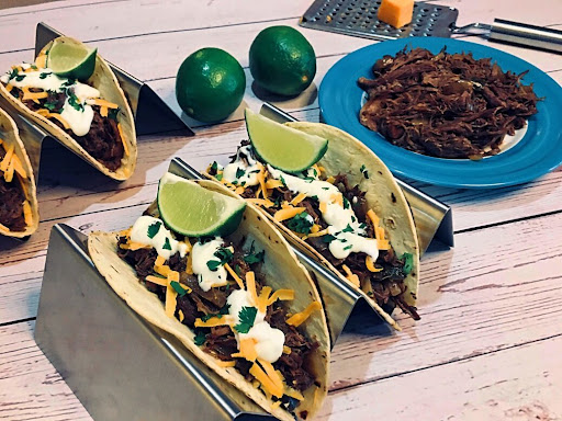 Two tortillas filled with a delicious & spicy Barbacoa Beef and topped with sour cream, cheese and cilantro.