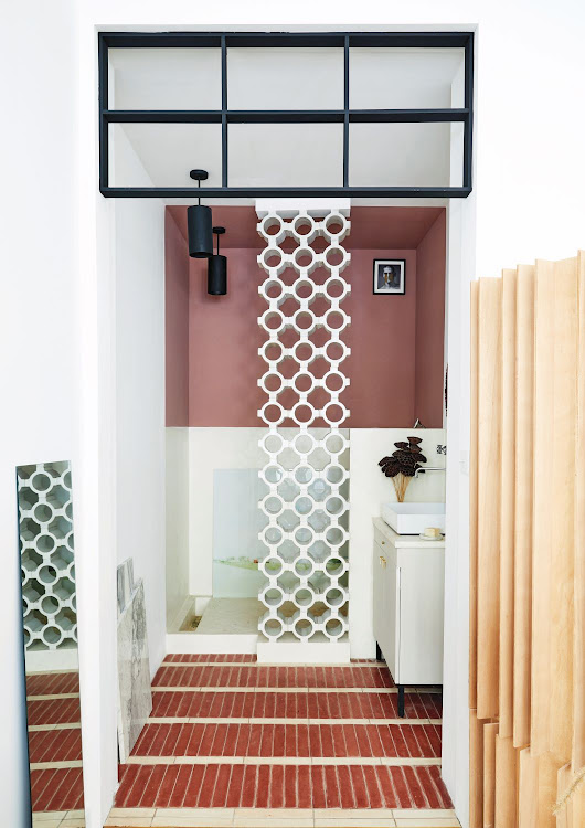 The intention in the bathroom was to create a tactile, visually engaging space.The shower was designed around the decorative flourish of the screen-like white panels that form a box and artfully contrast with the linear forms of the tiles, colour-blocked paint effect, and black grid.