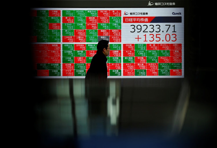 A man passes by an electronic screen displaying Japan's Nikkei share average. Picture: REUTERS/ISSEI KATO