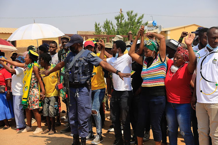 A police officer tries to control a group of protesting community members outside the home of slain ANC councillor Tshepo Motaung on Tuesday. A high-level delegation visited the family after Motaung was brutally killed on Friday.