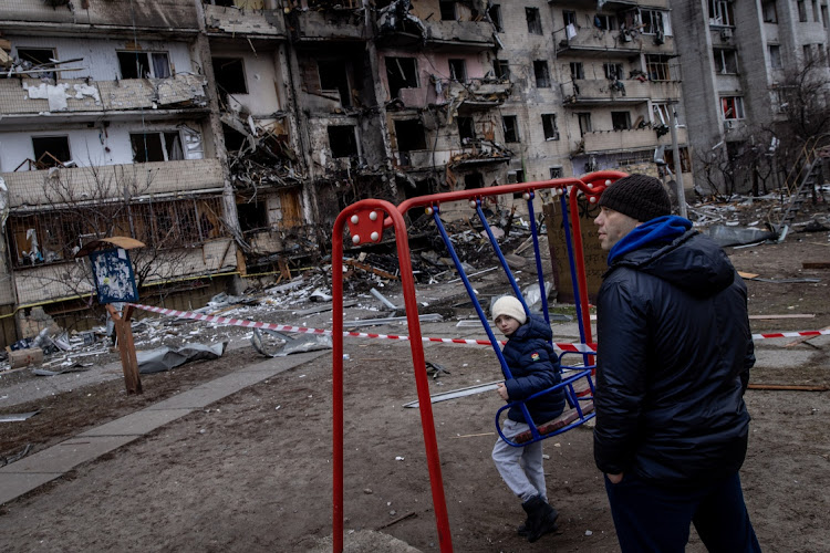 A boy plays on a swing in front of a damaged residential block hit by an early morning missile strike in Kyiv, Ukraine. Picture: CHRIS MCGRATH/GETTY IMAGES