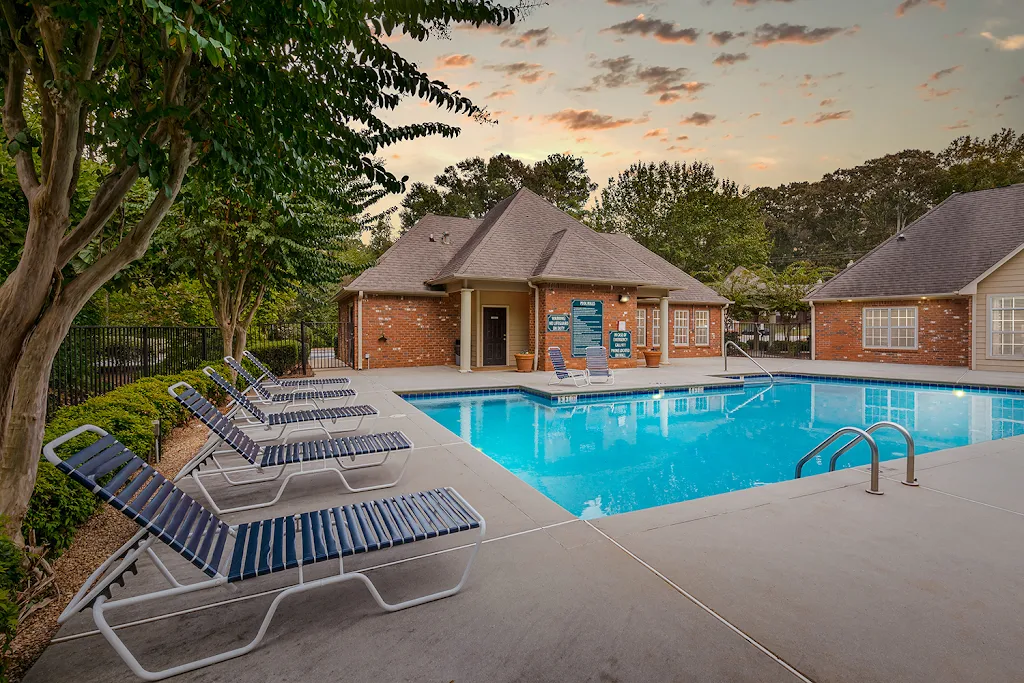 Refreshing swimming pool with lounge chairs by clubhouse at dusk