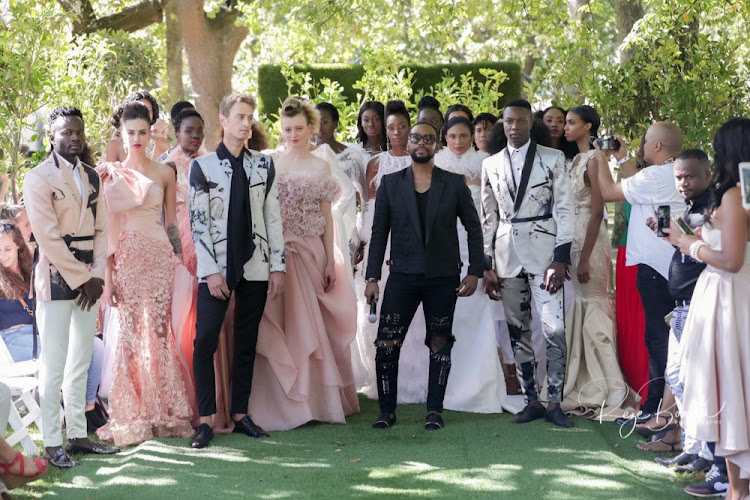 David Tlale stands with models wearing his designs at Boschendal.