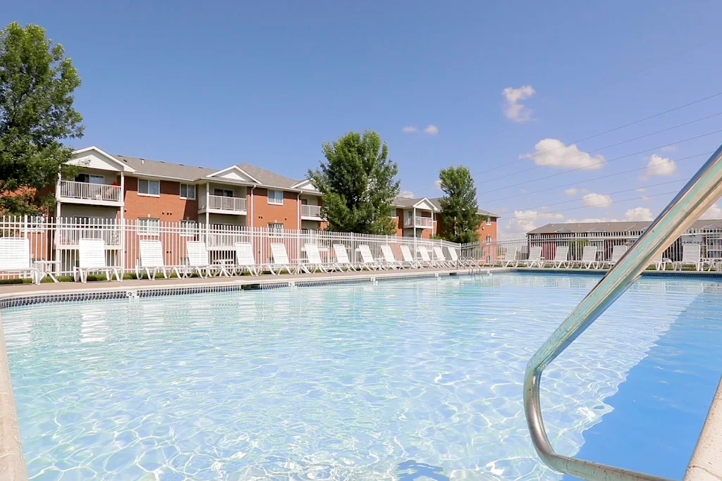 Lexington Ridge's swimming pool with white fence, white lounge chairs on sundeck, and apartment buildings in the background