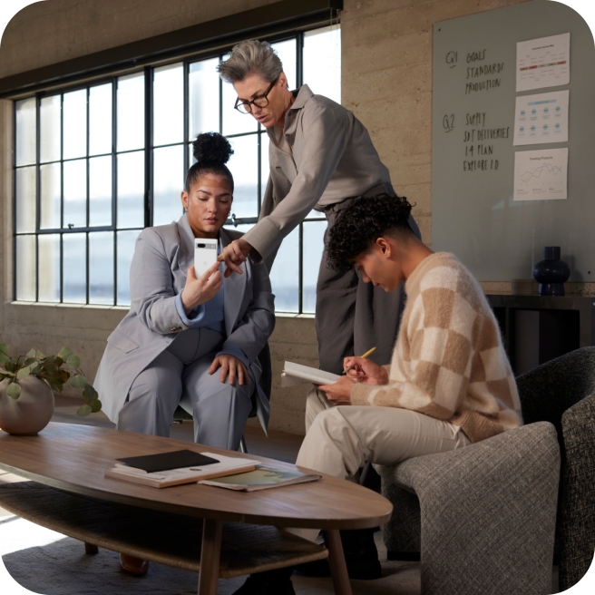 Three coworkers working with help from a Google Pixel 7a phone.