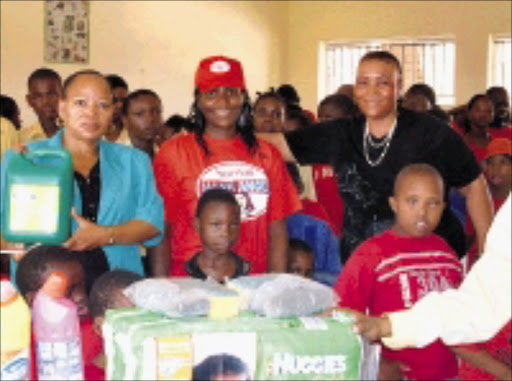 GIVING GIFTS: Mama Angel flanked by teacher Kgomotso Mailula, founder Baby Maphosa and the children of Ordirile Home in Hammanskraal, North West. Cicra 2009. Pic. Unknown