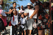 Natalia Nqabeni holds the hand of her daughter, Khayone Poro, as she sends her to her first day at Cosmo City Primary School.