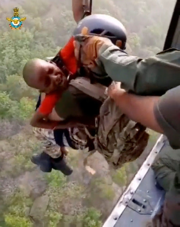 A rescuer carries a child to a helicopter during a rescue operation after a mid-air collision of two cable cars on Sunday trapped nearly 50 people in a dozen cars, in Deoghar district, Jharkhand state, India in this still image taken from a handout video obtained April 12, 2022.