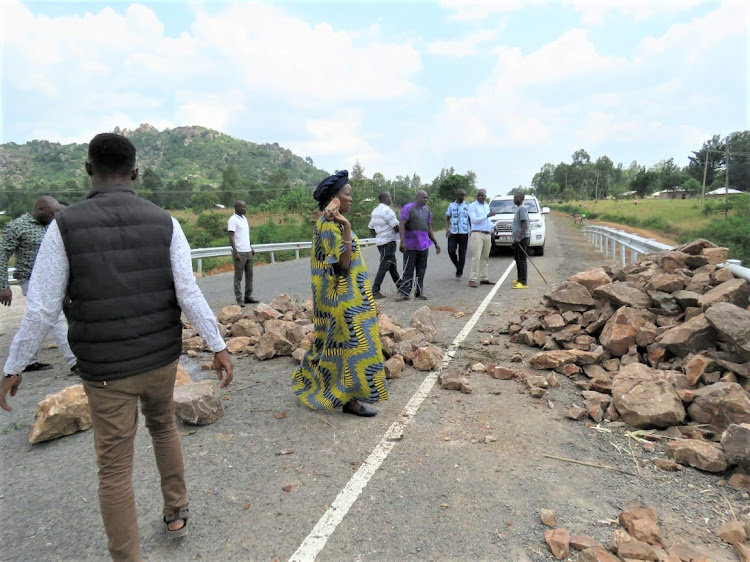 Emase carries stones to clear the road that had been barricaded at Lukolis.