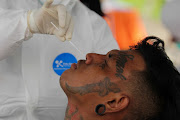 A healthcare worker takes a swab sample to test a person for coronavirus disease (COVID-19) in Surabaya, East Java Province, Indonesia.