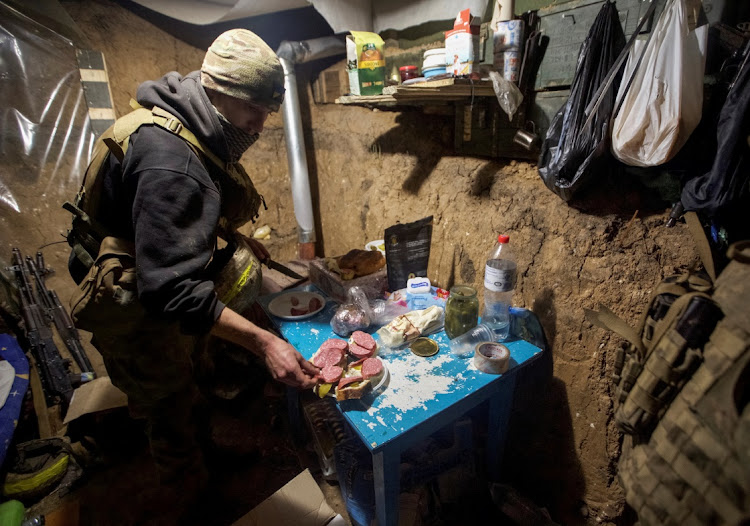 A Ukrainian service member prepares food in a shelter on the frontline in Donetsk on New Year’s say. Picture: ANNA KUDRIAVTSEVA/REUTERS