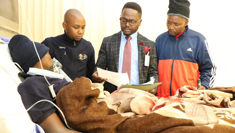 Nurse Henry Mkhalali, Nelson Mandela Academic Hospital clinical governance manager Dr Mphumzi Mdledle and a young initiate’s uncle watch over him in his hospital bed on Wednesday.