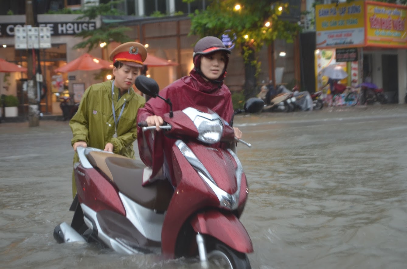 Một người phụ nữ được CSGT giúp đưa mô tô ra bị chết máy ra khỏi vùng ngập nước 