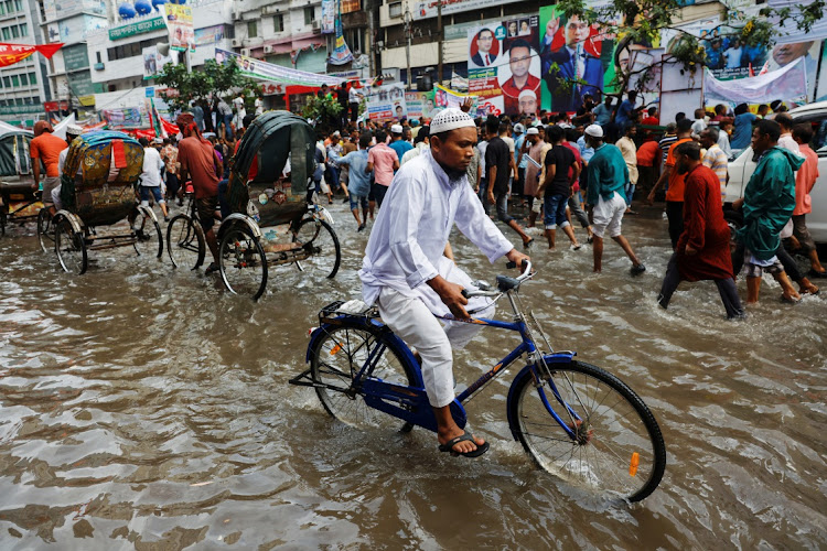 A man rides a bicycle on a flooded street after rain in Dhaka, Bangladesh, in August 2023. File photo.