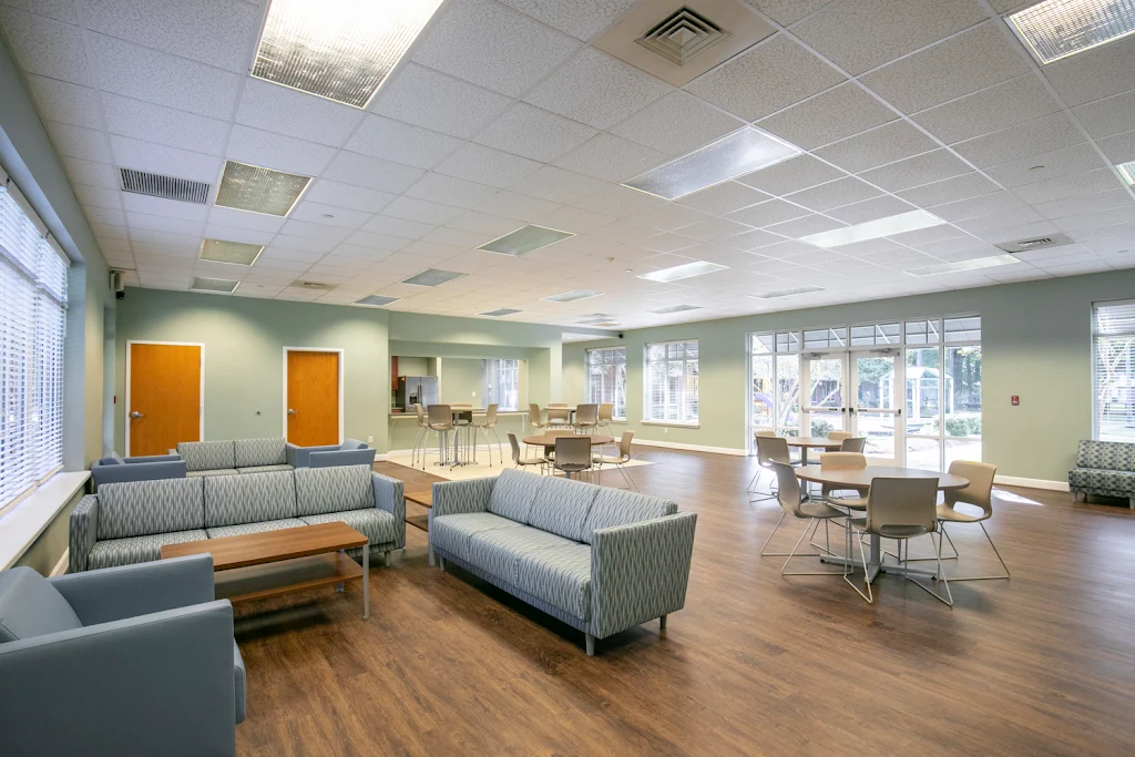 Community lounge area with chairs, kitchen, and tables