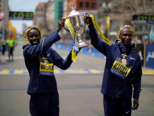 Women's division winner Edna Kiplagat (L) and men's division winner Geoffrey Kirui, both of Kenya, pose with the trophy at the finish line of the 121st Boston Marathon in Boston, Massachusetts. REUTERS