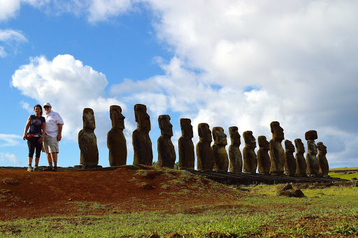 Visitors pose with a stand of moai figures on Easter Island.