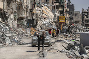 A man carries items on his back as people remove possessions from their homes following Israeli airstrikes on April 13, 2024 in Khan Yunis, Gaza. The Israeli military has scaled back ground troops in the southern Gaza Strip, leaving only one brigade. However Israeli officials have vowed to launch a ground invasion of Rafah at a later date.