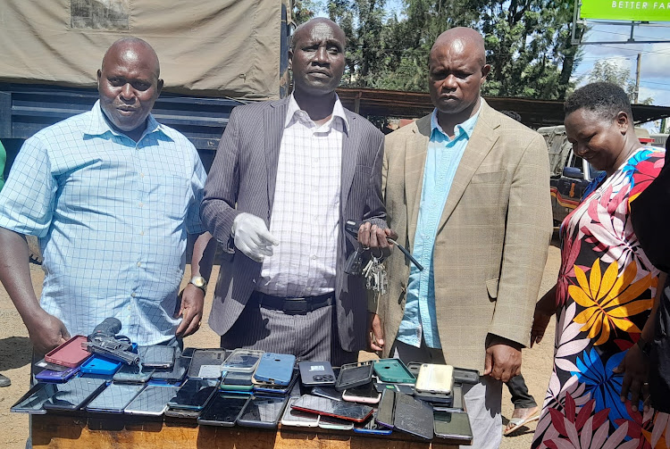 Uasin Gishu county police commander Benjamin Mwanthi (c) and county DCI boss Daniel Muleli (L) displaying items recovered from three suspects arrested in Eldoret