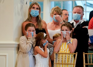 A group of attendees who had not been wearing protective face masks put on and wear masks provided to them by the White House because of the coronavirus (Covid-19) pandemic as they wait to watch US President Donald Trump hold a news conference at his golf resort in Bedminster, New Jersey, US, August 7, 2020.