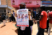 A demonstrator carries a poster depicting their colleagues during the procedural session of the trial of demonstrators accused of killing a police brigadier, outside the court in Khartoum, Sudan May 29, 2022.