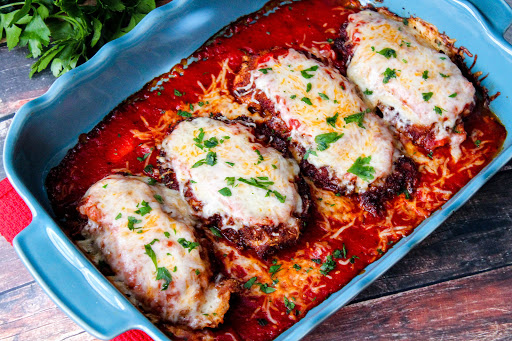 Chicken Parmigiana baked in a dish with melted cheese.