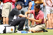 Louis Oosthuizen of South Africa receives treatment on the course after an arm injury on the second hole during the third round of the 2017 PGA Championship at Quail Hollow Club on August 12, 2017 in Charlotte, North Carolina.  