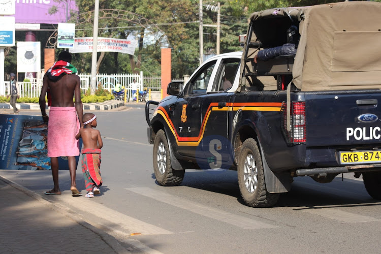 Police officers engage a man and his son donned in towels protesting along Jomo Kenyatta Avenue in Kisumu on July 19, 2023.