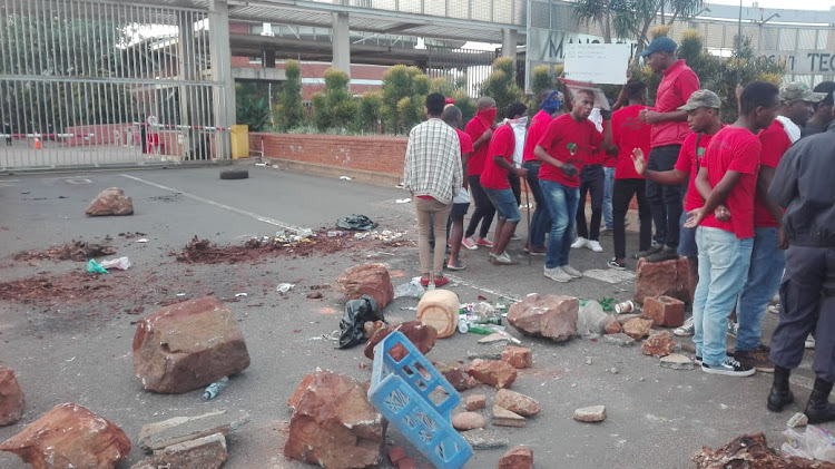 Mangosuthu University of Technology students use bricks to barricade the entrance to the institution on Monday.