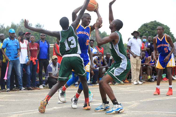 Alvin Otieno of Onjiko School is blocked by Agoro Sare's Cedrick Pele (R) Luoje Nick during the boy's basketball final