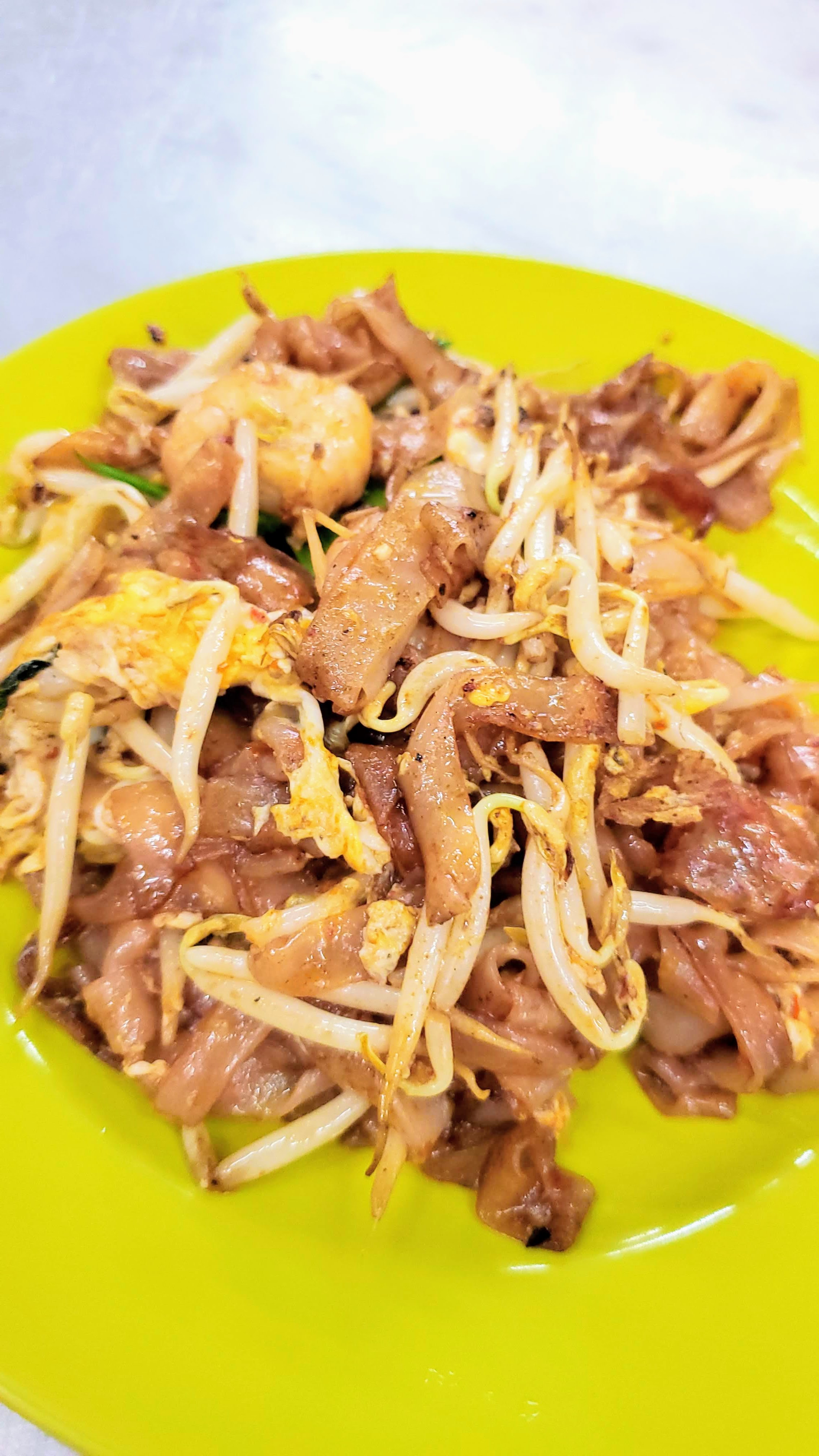 Food Highlights of Penang: Char Koay Teow, considered an iconic street food in Penang. This is a dish of stir fried rice cake strips with flat rice noodles stir-fried in pork fat with light and dark soy sauce, chili, belachan (fermented shrimp paste), prawns, blood cockles, bean sprouts, chopped Chinese chives, and egg. Usually this is by default a chicken egg, but you may have an option to upgrade to a duck egg for a bit more richness