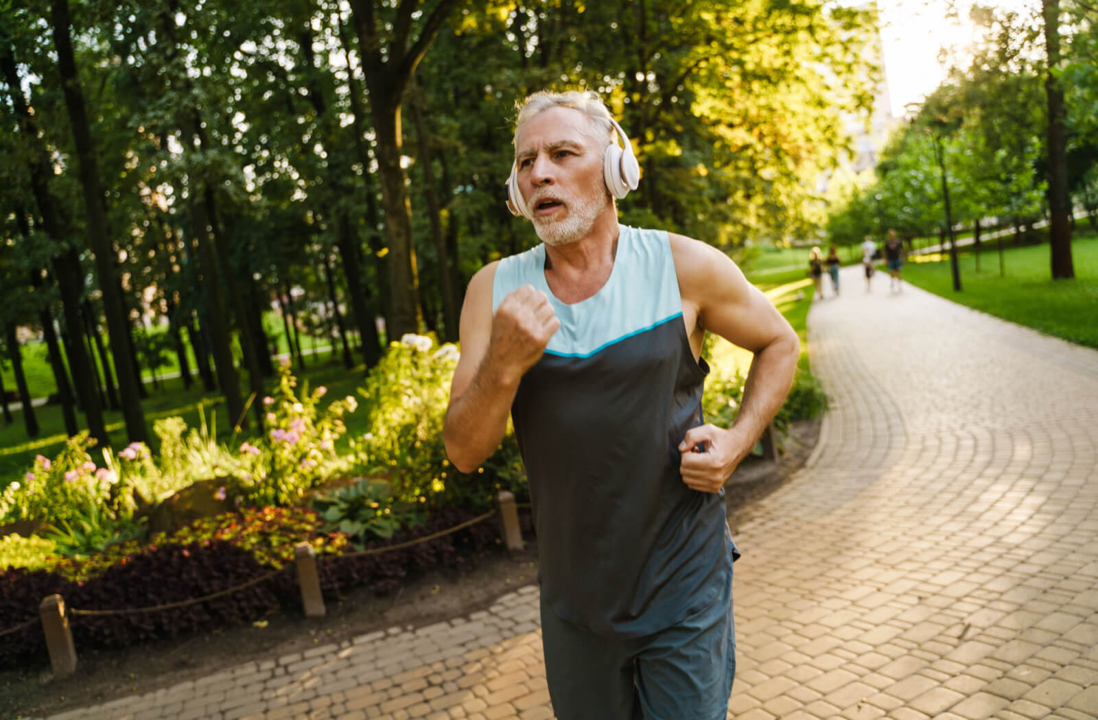 A senior man listening to music while on his morning jog in the park.