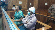 Rosemary Ndlovu (left) and Nomsa Mudau seated next to each other in the Kempton Park regional court. The pair stand accused of conspiring to kill Mudau's husband, Justice, in February 2018. 