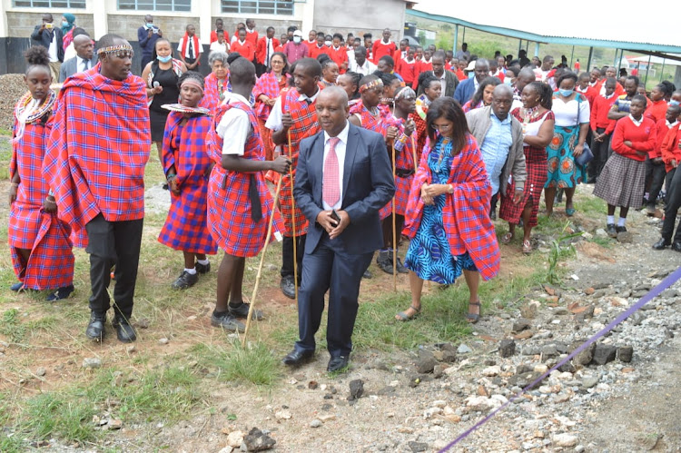 Empakasi Secondary School infrastructure committee chairman Jeremiah Kaloi (in suit) with Amara NGO officials, teachers, parents, students alongside members of the public during the commissioning of newly constructed dormitories, kitchen and dining hall at the school in Athi River North, Machakos on Monday, January 24.