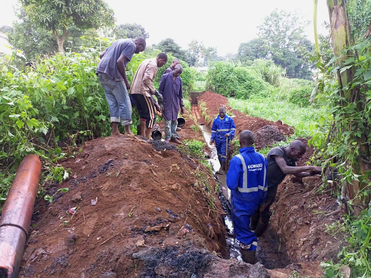 Workers from the Kakamega County Water and Sanitation Company-KACWASCO dig water connection trenches.