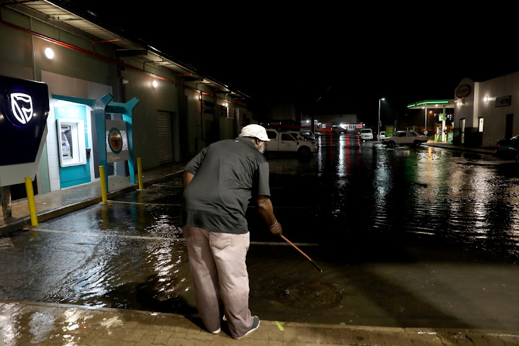 A man drains water at Dube Village Mall, which flooded after heavy rains in Inanda, north of Durban.