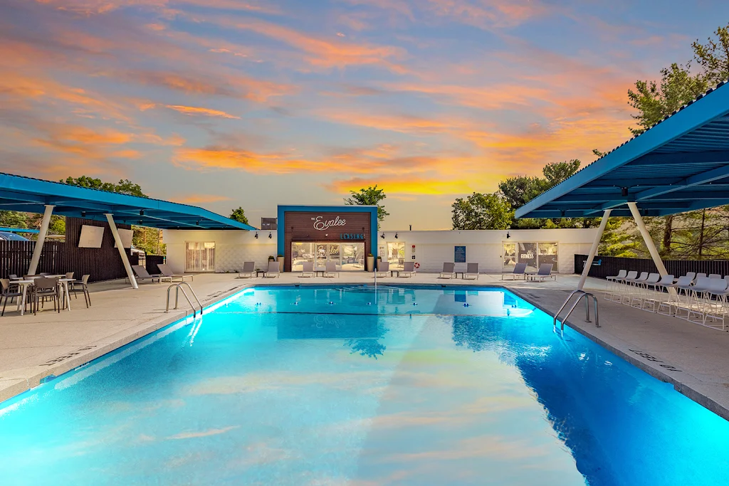 The Evalee's swimming pool with lounge chairs, next to the clubhouse, at dusk