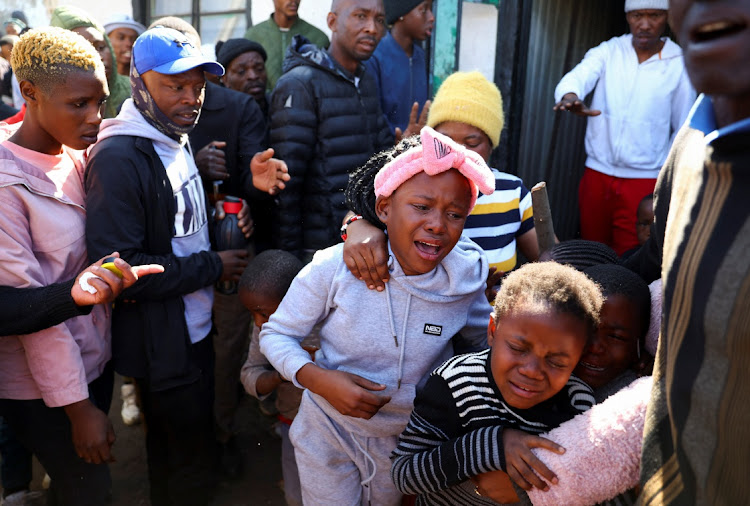 Children react as community members burned shacks and belongings as they searched for alleged illegal miners known as ‘zama-zamas’ as a protest, following alleged rape of eight models on July 28 when a television crew filmed a music video at a mine dump in the nearby township, in the West Rand, South Africa, August 8, 2022.