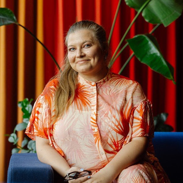 Sofia Sharkova, responsable de l’inclusion chez Google à Zurich, est assise dans le coin d'un canapé bleu, devant une plante.