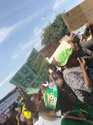 Scores of people protest outside the Lenasia Magistrates Court ahead of the appearance of two people implicated in the killing of seven family members in Vlakfontein.   