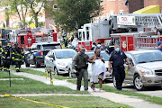 Police officers help a woman at the scene of an explosion in a residential area of Baltimore, Maryland, US, on August 10 2020. 