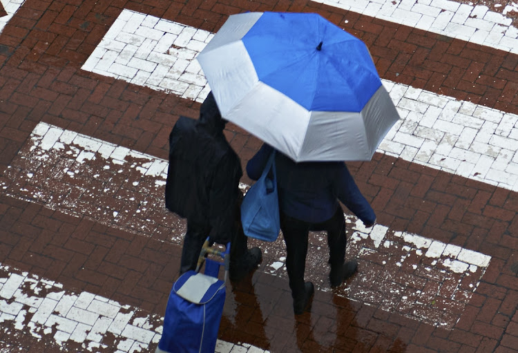 Pedestrians brave the rain crossing Cavendish Street in Claremont, Cape Town on Cape Town June 13 2022. The worst affected areas are informal settlements in Khayelitsha, Ottery, Langa, Strand, Philippi, Gugulethu, Delft and Vrygrond.