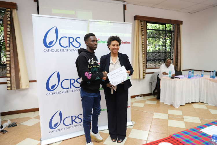 CRS country representative Rebecca Hallam (right) presents a scholarship award certificate to Lawrence Wainaina to study electrical wiring in Waithaka Vocation Training Institute.