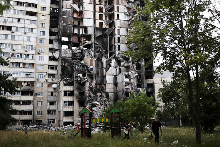 Neighbours walk next to a building destroyed by a military strike, as Russia's invasion of Ukraine continues, in northern Saltivka, in Kharkiv, Ukraine, on July 13 2022.