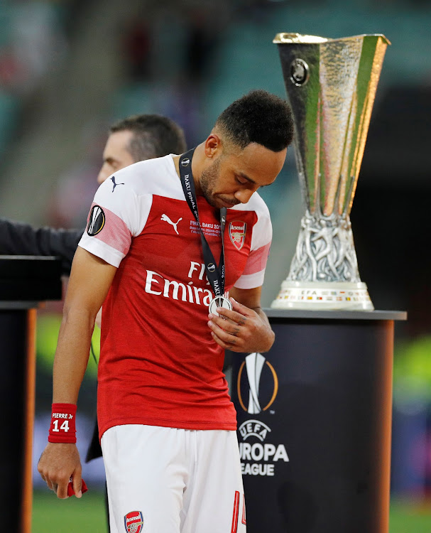 Arsenal's Pierre-Emerick Aubameyang looks dejected as he walks past the Europa League trophy